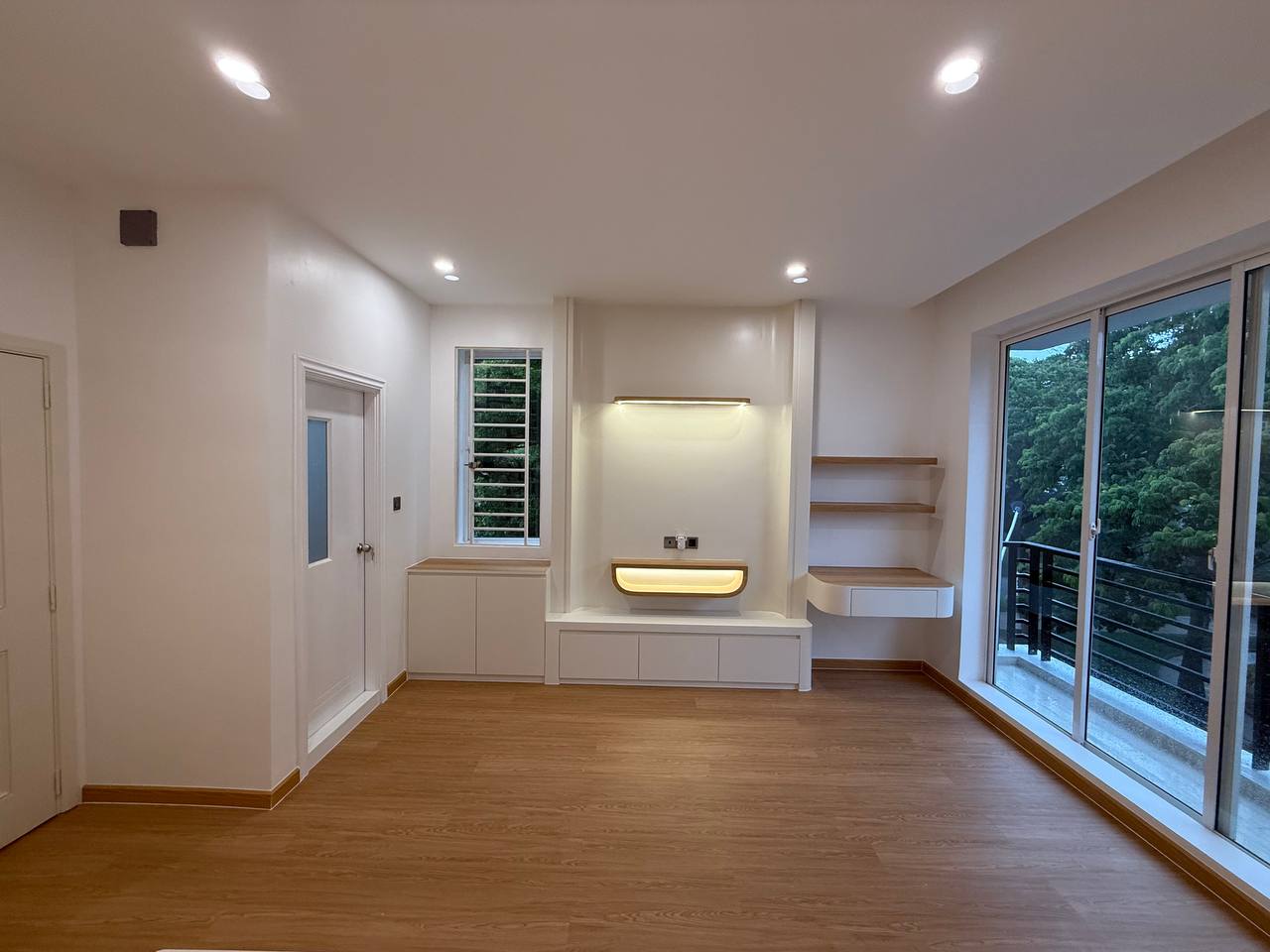 Open room with wood-toned floor, wall niches and large glass doors