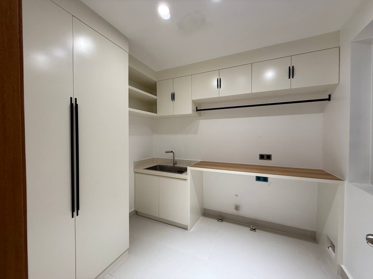 Compact kitchen area with sink, cabinetry and white work surfaces