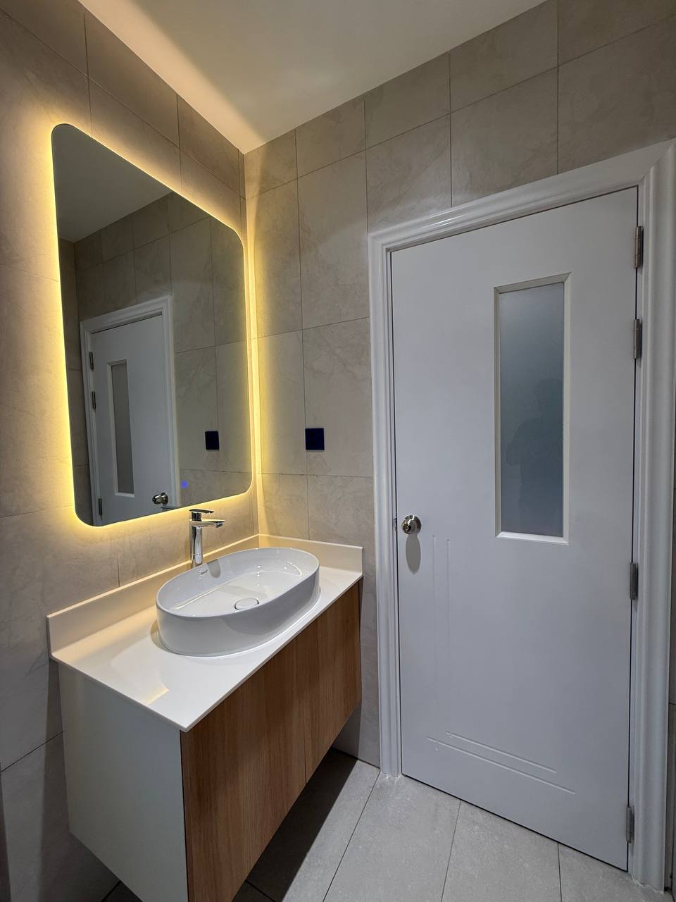 Vanity basin with backlit mirror and wood-toned cabinet