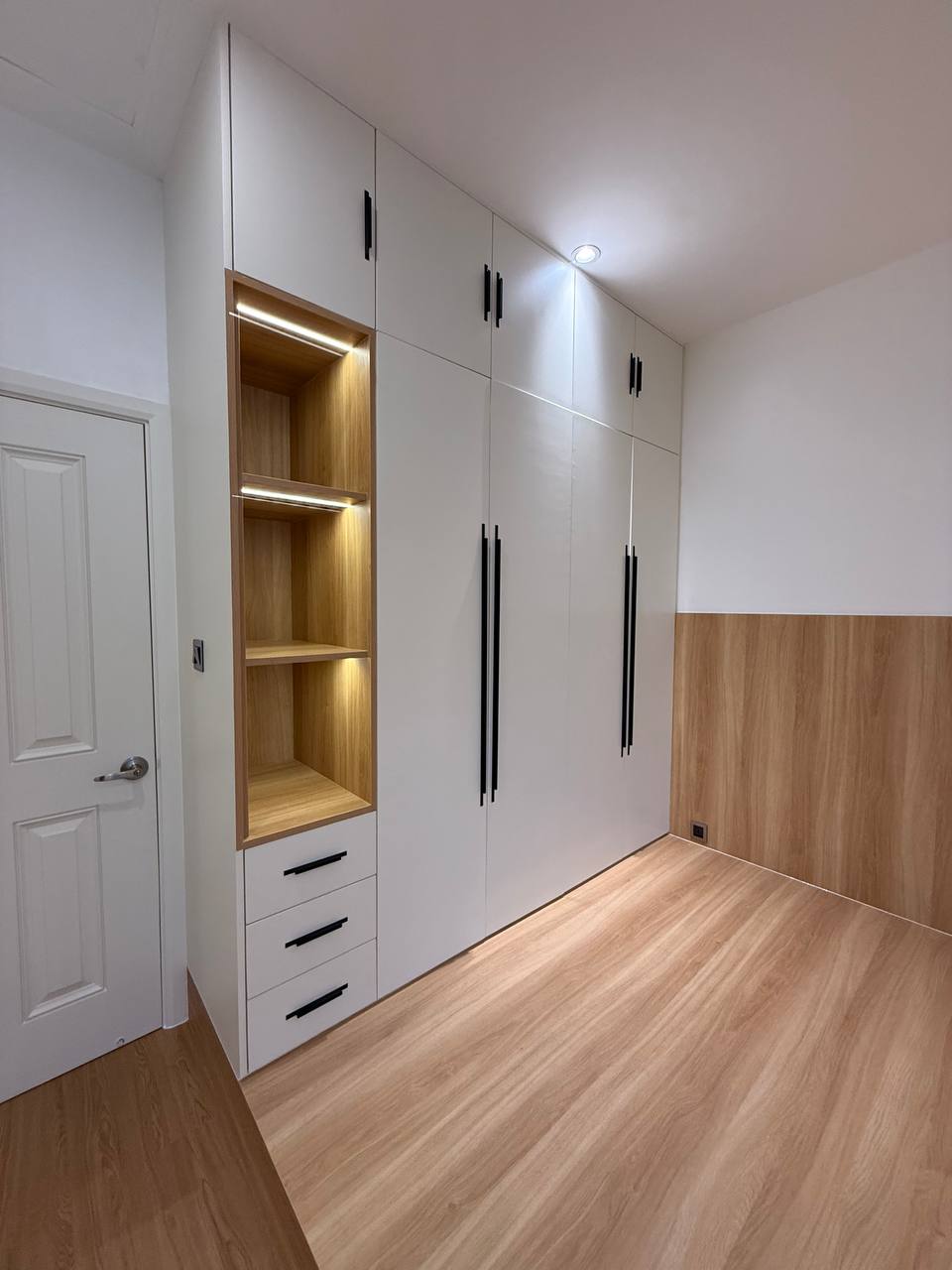 Tall white wardrobe with wood-toned illuminated shelf and drawers